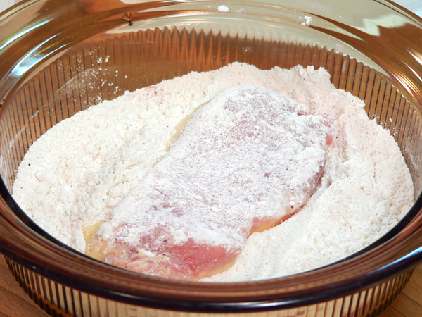 18_Pork-Chops_dredge-flour Place one of the chops in the flour breader mix.